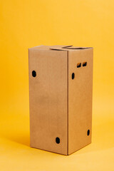 brown closed cardboard box on yellow background. suitable for storing bottles or kegs