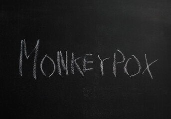 Obraz premium The word Monkeypox is written in white chalk on a black board. There is an outbreak of monkeypox in the world. A new global epidemic.