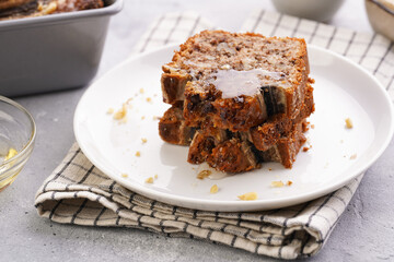 Slices of Chocolate banana bread with walnuts on a checkered kitchen napkin and ingredients on a grey neutral background