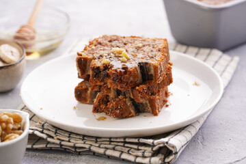 Slices of Chocolate banana bread with walnuts on a checkered kitchen napkin and ingredients on a grey neutral background