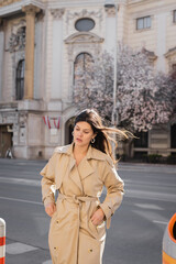 woman in elegant coat standing on windy street in vienna.