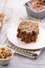 Slices of Chocolate banana bread with walnuts on a checkered kitchen napkin and ingredients on a grey neutral background