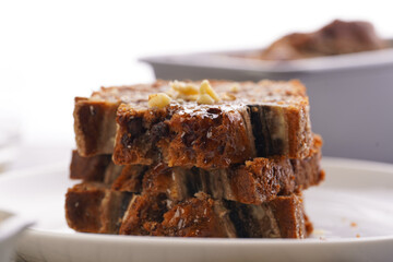 Slices of Chocolate banana bread with walnuts on a checkered kitchen napkin and ingredients on a grey neutral background