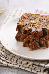 Slices of Chocolate banana bread with walnuts on a checkered kitchen napkin and ingredients on a grey neutral background