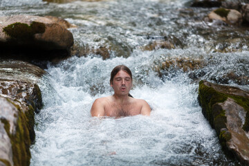 Mid Adult Man Taking a Ice Cold Bath in Wild Water Stream in Alps. Wim Hoff Method therapy of Breathing in Cold Environment