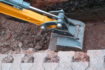 excavator bucket digs earth in trench on street, concept of repairing urban communications,...