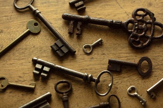 Encryption and Security concept image. Old and vintage keys, arranged randomly, many from 1800s, on an old grungy wooden desk. Top view.