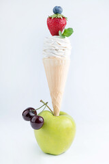 ON a white background, an apple, a waffle cup with marshmallows and strawberries.