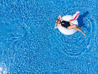 Woman on unicorn pool float in pool in hotel. Summer holidays. Aerial top view from drone