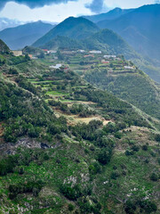 Fototapeta na wymiar Volcanic mountains covered with tropical forests and an alpine village with terraces for agriculture