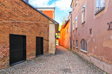 Fototapeta na wymiar Medieval narrow alley in Turku, Finland called Luostarin välikatu. It used to lead from the monastery to the city centre and the cathedral visible in the background.