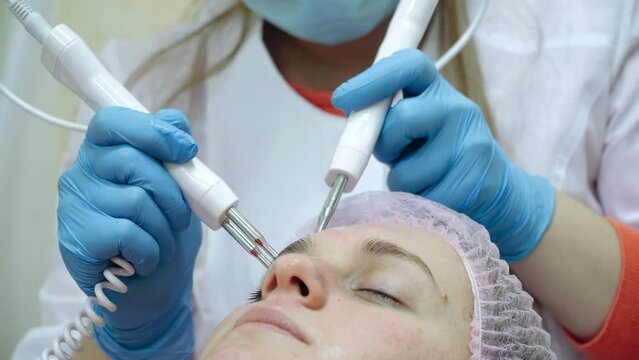 Beautiful woman receiving facial microcurrent treatment at spa salon.