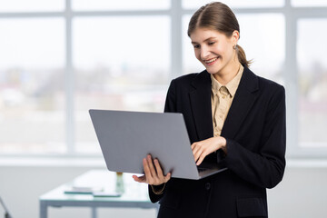Portrait of young businesswoman holding silver laptop in the office