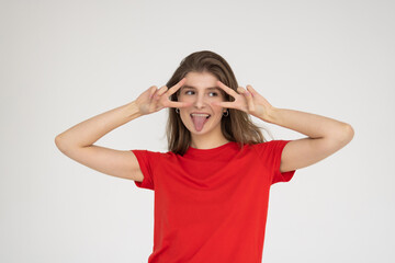 Young woman wearing casual t-shirt showing peace sign with fingers isolated over gray background