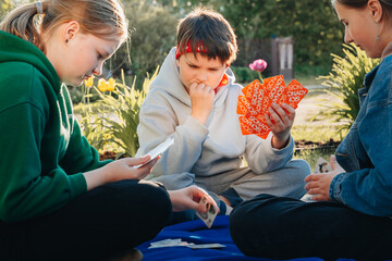 Happy young teen playing card game in backyard. Spending leisure vacation time with friends concept.training memory, thinking. Development step and education of children. vacation time with friends  © Natallia