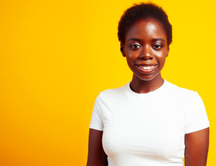 pretty young african american woman with curly hair posing cheerful gesturing on yellow background, lifestyle people concept