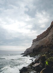 Fototapeta na wymiar waves crashing on rocks with cliff