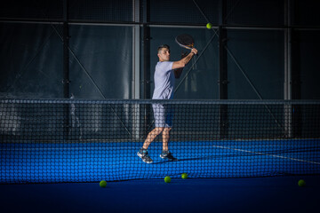 Fototapeta na wymiar Man playing padel tennis indoor