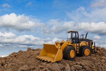 Obraz na płótnie Canvas Wheel loader are digging the soil in the construction site on sky background ,with white fluffy cloud