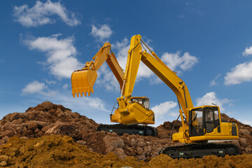 Two Excavator  are digging  soil in the construction site on sky  background,with white fluffy cloud