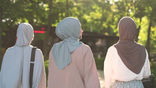 Rear view of three muslim women talking while walking outdoors