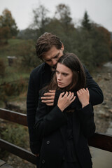 A young couple in love in black coats walks in the countryside in the rain. Autumn gloomy mood. cinematic image