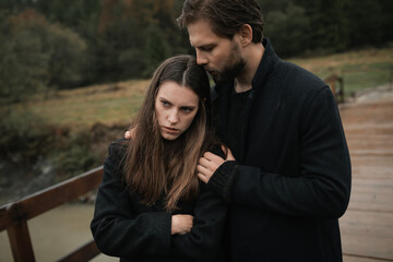 A young couple in love in black coats walks in the countryside in the rain. Autumn gloomy mood. cinematic image