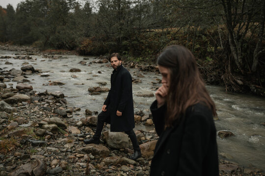 A young couple in love in black coats walks in the countryside in the rain. Autumn gloomy mood. cinematic image