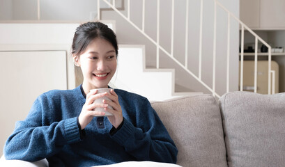 Portrait of smiling happy cheerful beautiful pretty asian woman relaxing drink. Girl felling enjoy having breakfast in holiday morning vacation on sofa at home