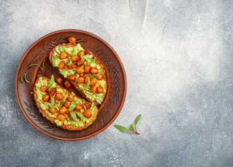 Healthy vegan and vegetarian rye bread sandwiches with avocado, chickpeas, spices and microgins (green shoots). Delicious gourmet breakfast in a clay plate. Selective focus, top view, copy space
