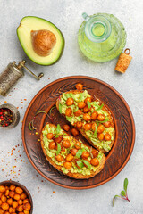 Healthy vegan and vegetarian rye bread sandwiches with avocado, chickpeas, spices and microgins (green shoots). Delicious gourmet breakfast in a clay plate. Selective focus, top view