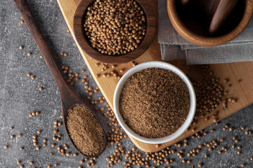 Coriander powder and coriander beans in a wooden spoon. Dry coriander. Coriander seed spice.