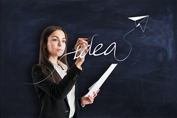 Creative idea and strategy concept with young woman on blackboard background writing idea word with paper plane