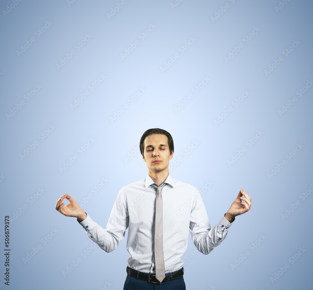 Poster calm down concept with man in white shirt in a zen pose isolated on light blue wall background with 