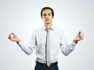 Relax and tranquility concept with young handsom man with closed eyes in zen pose isolated on light grey wall background, close up