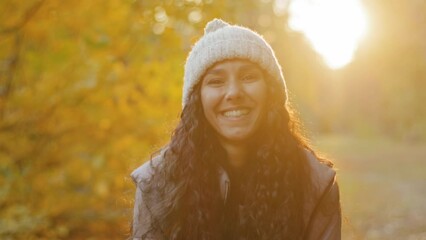 Close-up young pretty hispanic woman looking at camera smiling beside herself with happiness attractive curly girl stands in autumn park poses outdoors in sunshine rejoices laughs enjoys feeling joy