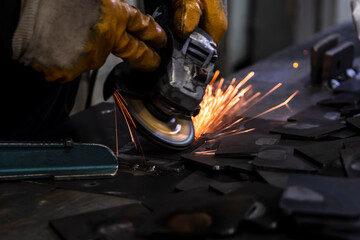 Grinding metal plates with electric wheel in factory. Sparks from the grinding wheel. Selective focus grinding machine and metal plates. Motion blur sparks