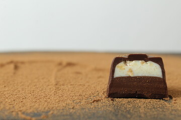 body chocolate candy with chocolate and white milk cream filling close-up against the cocoa background. A day of chocolate sweets without diet. handmade sweets