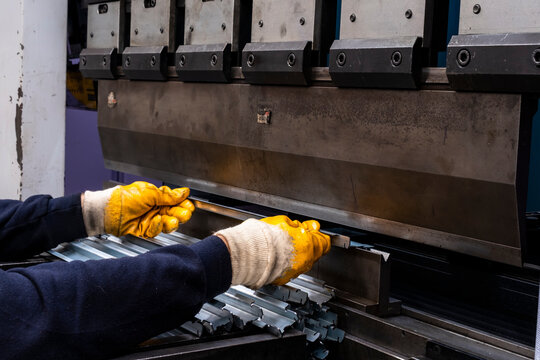 hydraulic press brake or bending machine for flat sheet metal. Worker bending sheet metal on the machine.