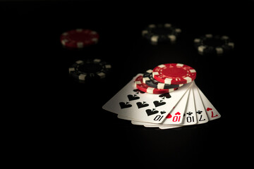 Playing cards on a black table with full house or full boat poker winning combination and chips in the background.