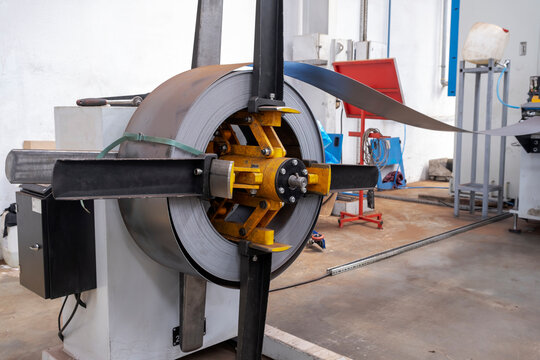 Roll of Steel on factory decoiler machine. used to make roofing sheets. Metal roll being uncoiled
