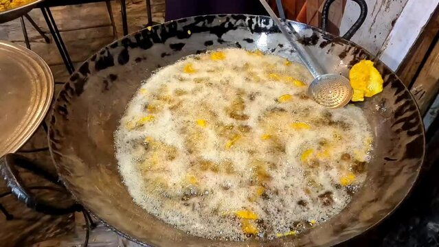 Frying french fries in huge pan with hot oil 4k high resolution clip
