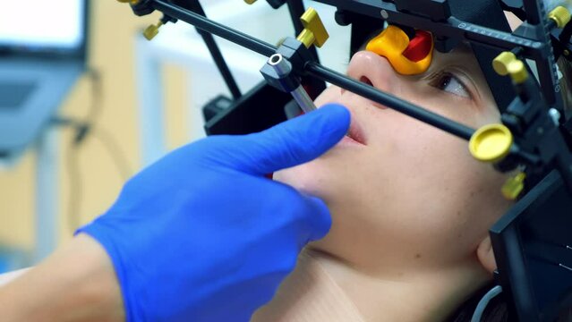 Orthodontology treatment and cure concept. Orthodontist is doing condylography, woman patient is moving her lower jaw. Examination and treatment of mandibular joints. Dentistry and clinic.