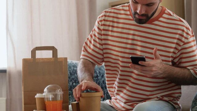 communication, leisure and people concept - man using smartphone for takeaway food order check up at home