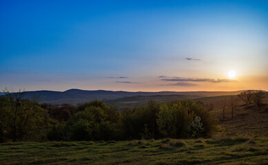 Field with plants in the valley against the backdrop of the sunset sky in Bulgaria