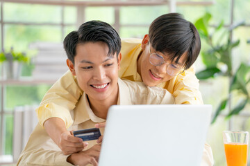 Couple gay or lgbt man enjoy to online shopping together using laptop and stay in living room with day light.