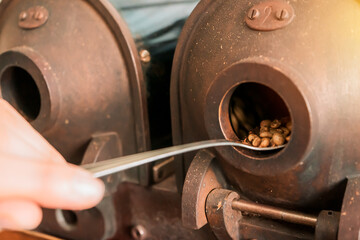 Closeup on the hand of a Latin woman grinding coffee in a vintage manual machine