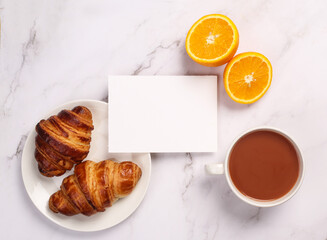 Morning breakfast setup on white surface. Flat lay of croissant, oranges, sourdough and coffee lying around.