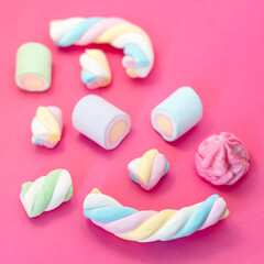 Marshmallows on pink background. Assortment of candies and sweets in pink background. Marshmallow in pastel colours with copy space.