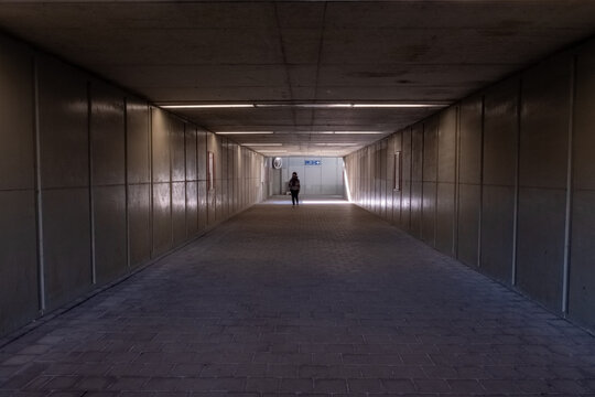 The woman walks down the tunnel towards the light. Silhouette of a woman walking in the underpass. High quality photo